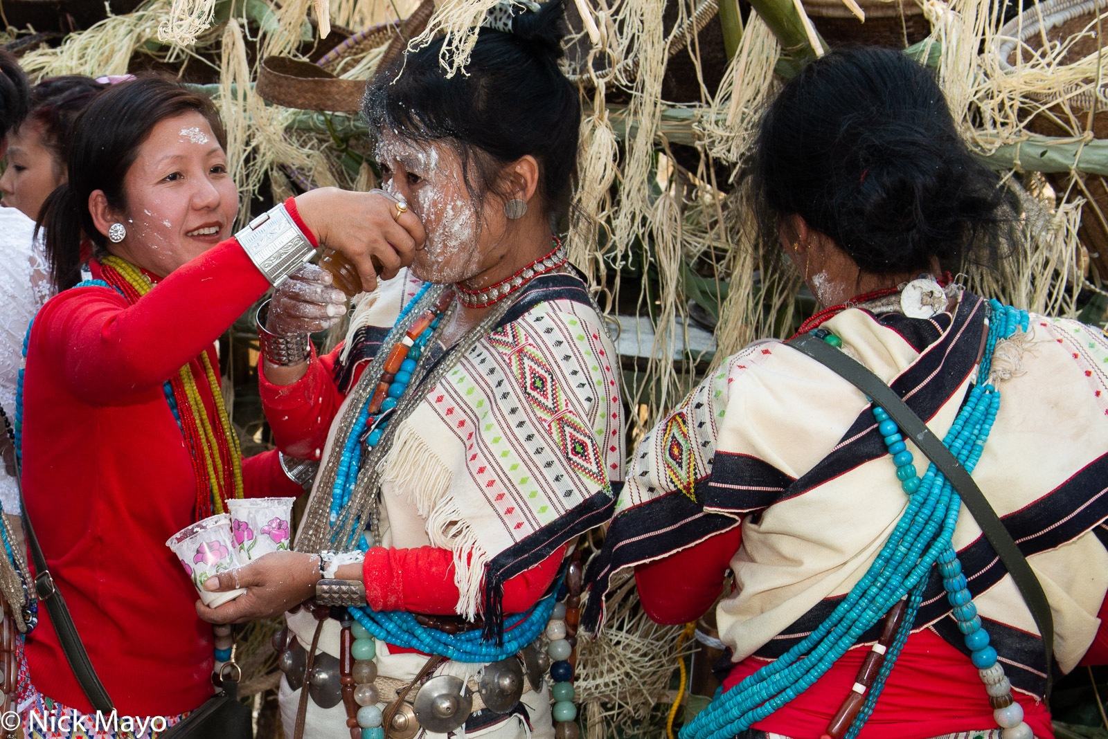 A Nyishi woman coated in rice powder drinking beer at the finale of the Tamen Boori Boot festival.