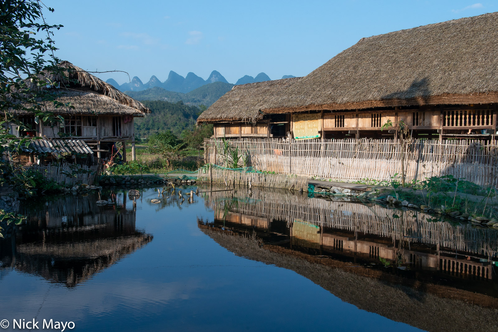 A thatched house reflected in a pond in the village of Thon Tha.