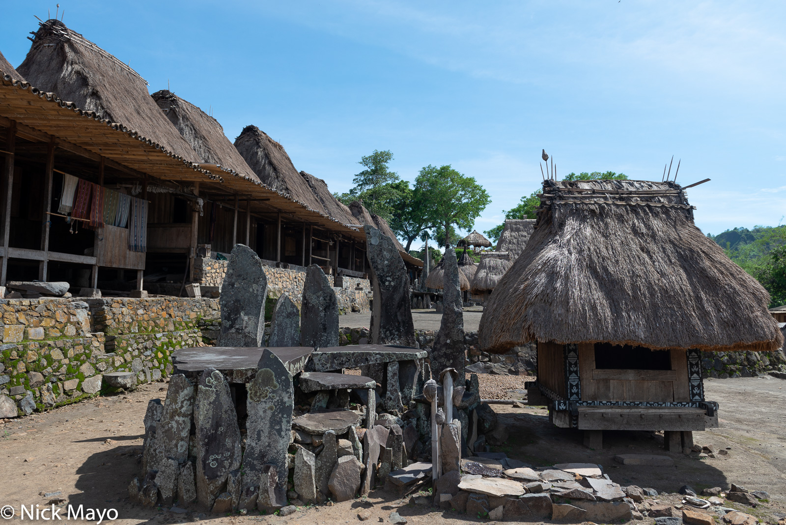 A watu lewa (stone altar) and thatched roofed bhaga in the Ngada Regency village of Bena.