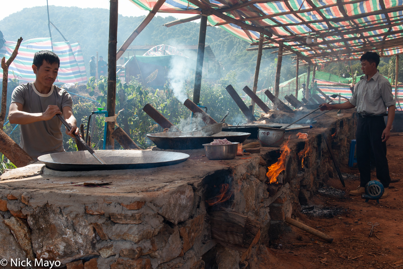 Men cooking a group lunch on large woks at a Lisu New Year festival in Mogok.