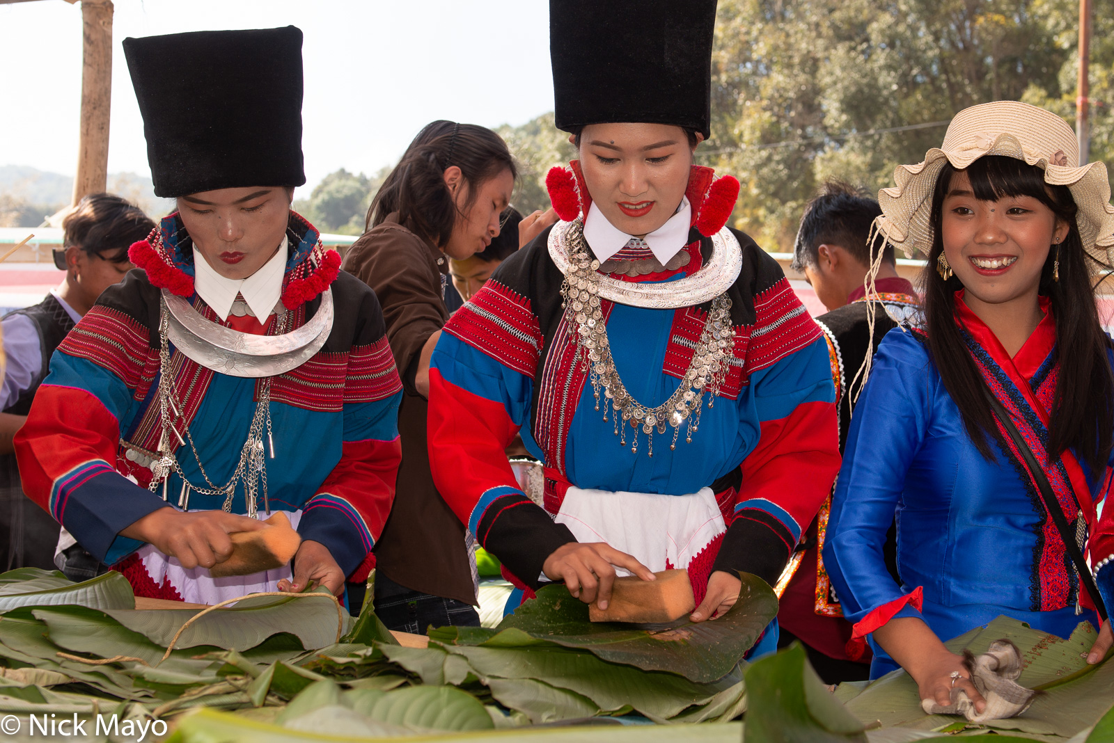 Traditionally dressed women preparing leaves to be used as platters for a meal at a Lisu New Year festival in Mogok.
