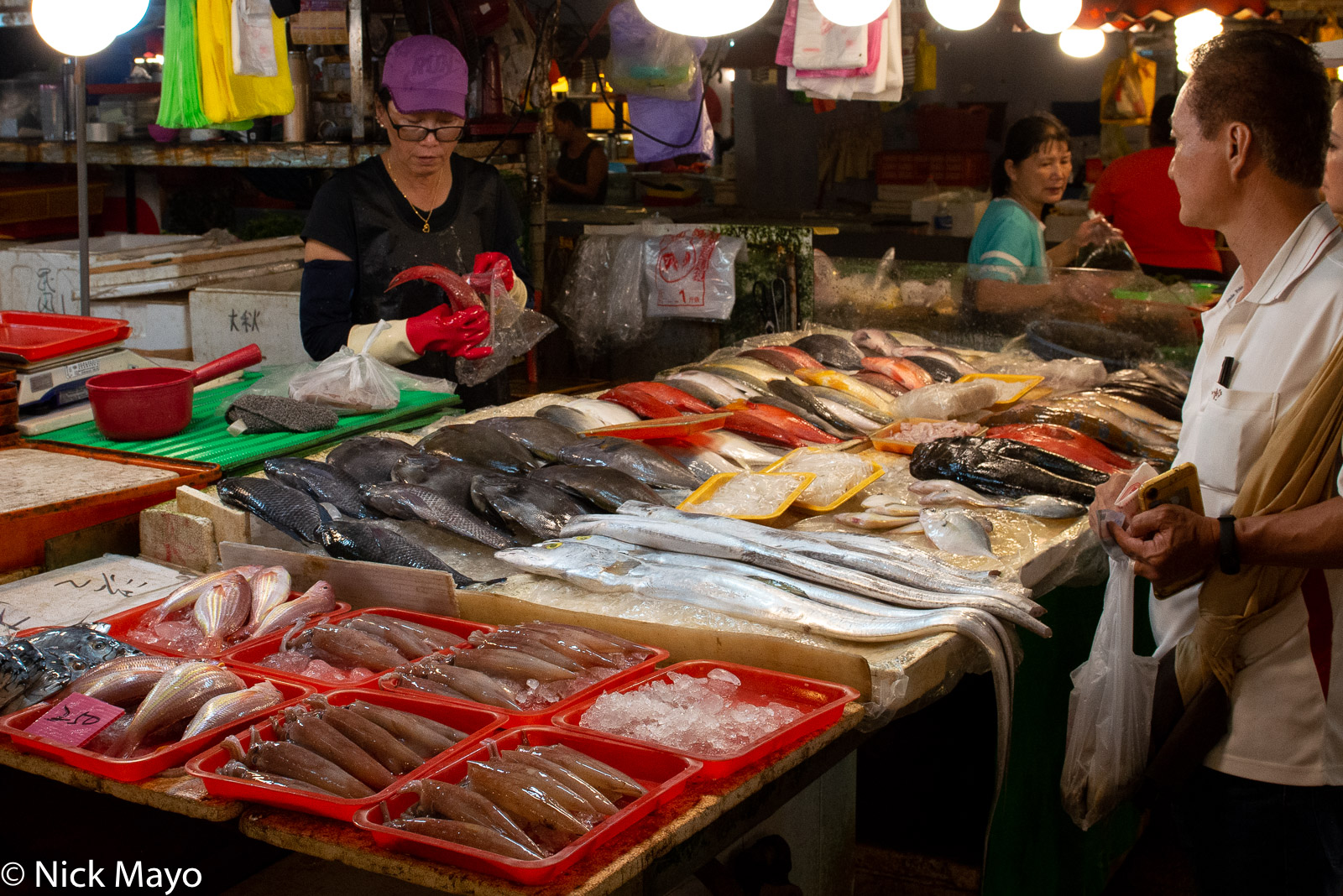A stand owner selling fish at Huaqiao market in Donggang.