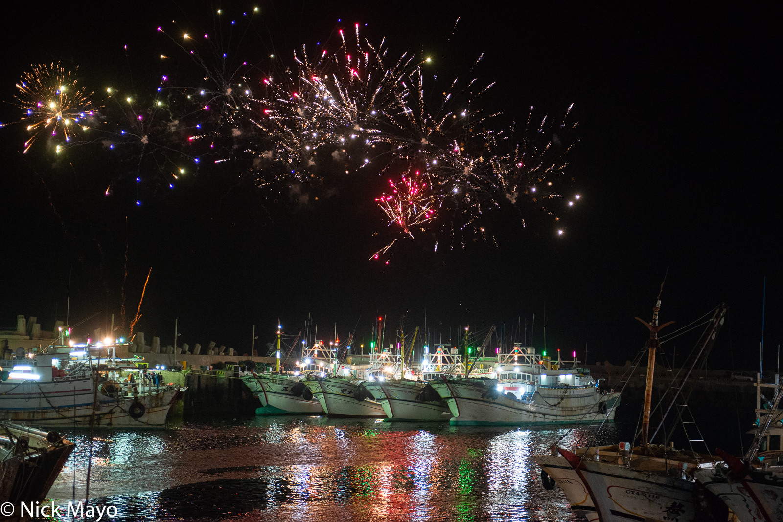 Festival fireworks bursting over fishing boats in Wai'an harbour.