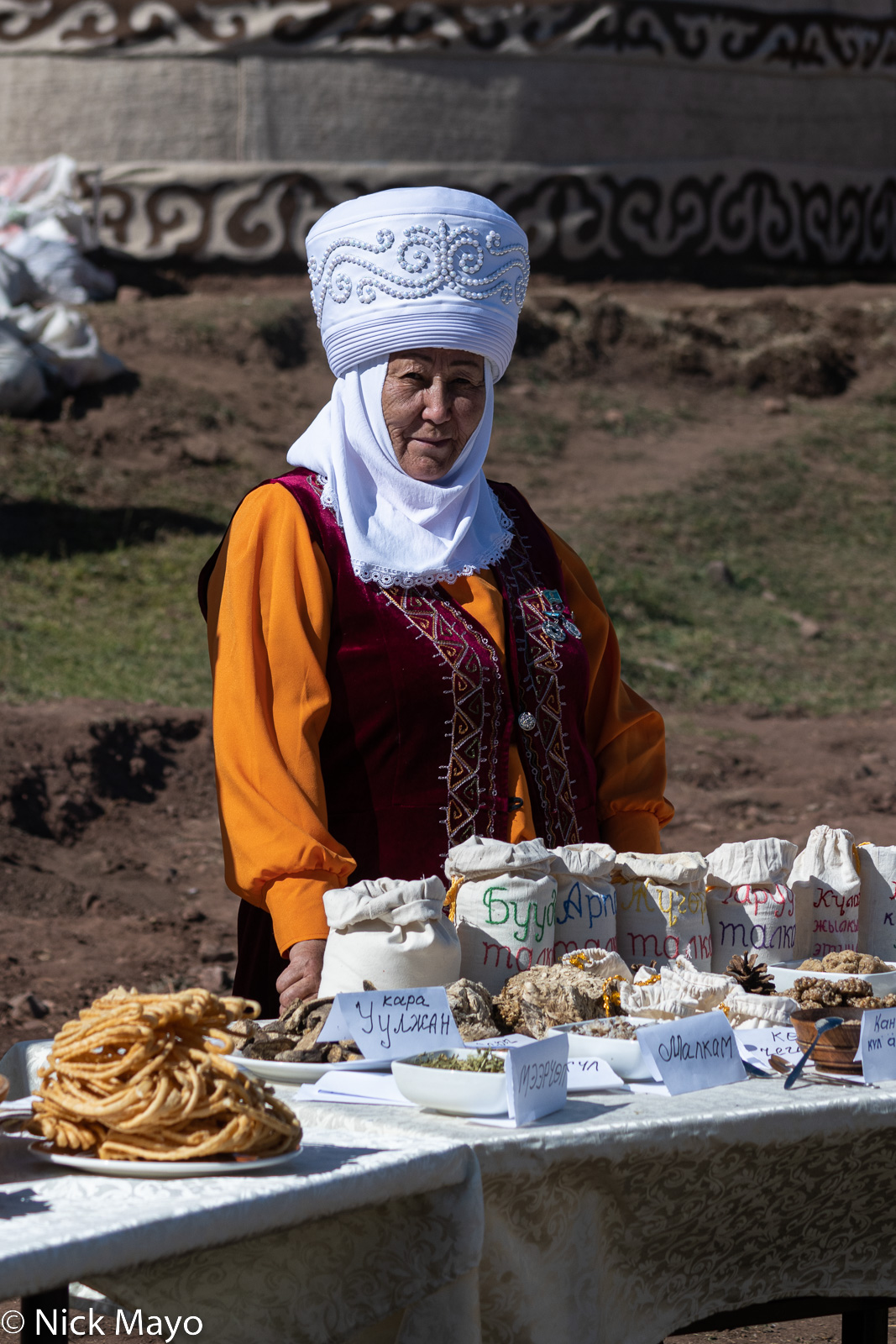An attendee in traditional dress and elechek headdress at the Independence Day festival at Chunkurchak.