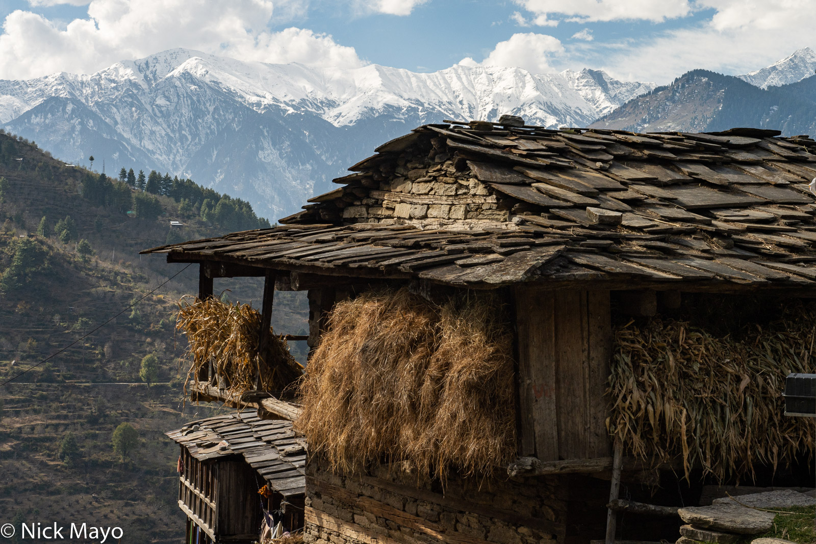 Hay and corn hung on a traditional slate roofed Kulu house in Hallan-I village.